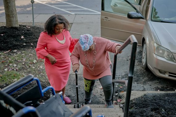 A photo of a woman helping her elderly mother up the stairs.