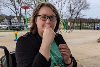 A photo shows Courtney Johnson sitting outside at a park.