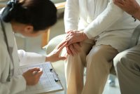 A photo of a doctor examining an elderly patient's knee.
