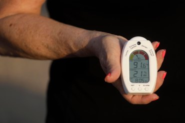 A photo of a woman holding a temperature and humidity reading device.