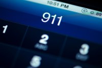 A photo of someone dialing 911 on a smartphone.